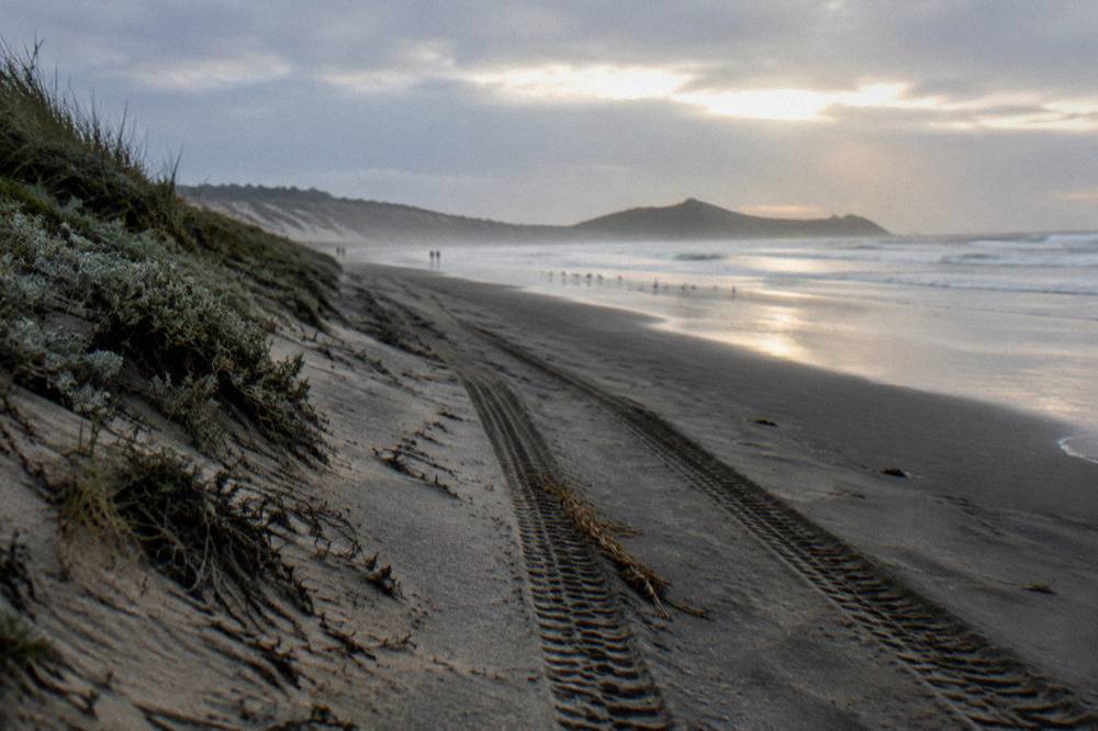 A four wheel drive track on wet sand beside a long open beach at Stockton Bight