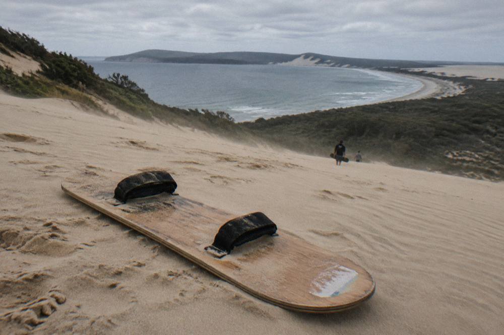 A sandboard resting on a sloping dune at Stockton Bight with wind ripples in the sand