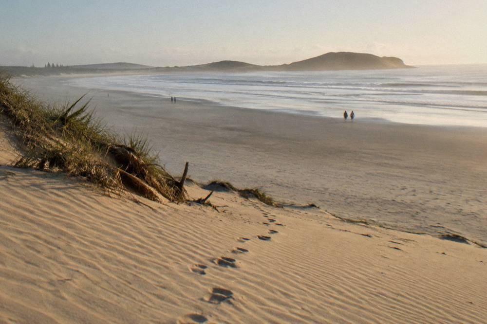 A wide sandy slope at Anna Bay with footprints trailing down toward the flat sand below