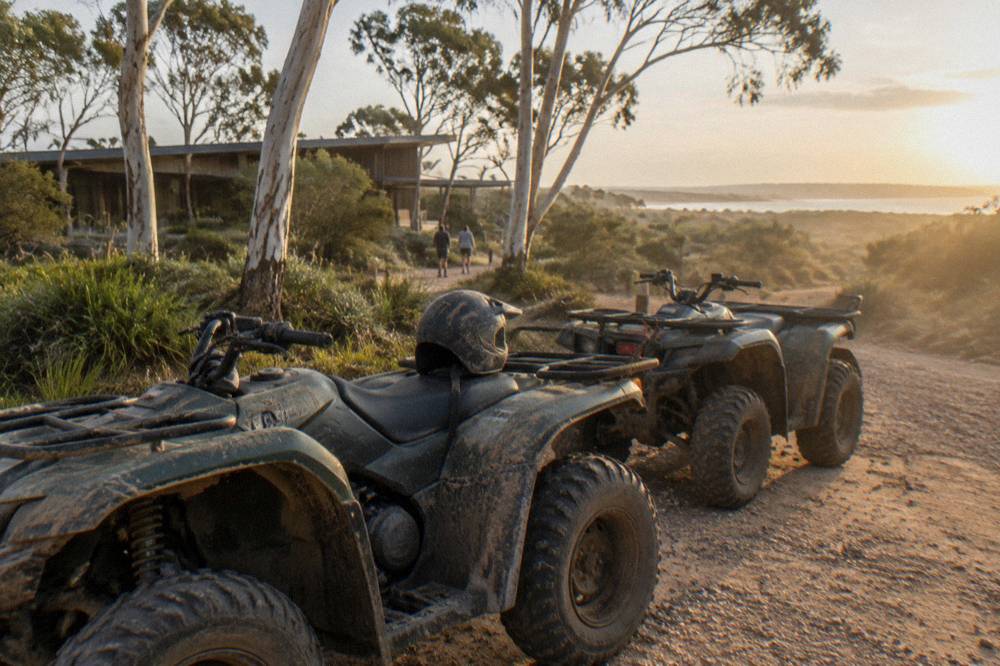 A four wheel drive vehicle on firm wet sand at the base of tall sand dunes