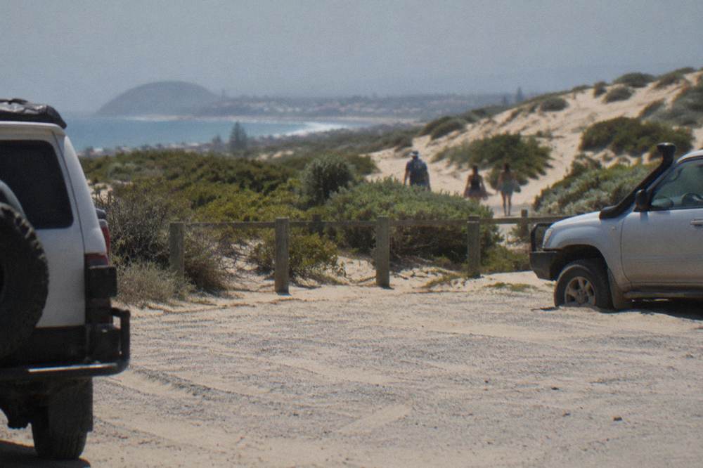 A sandy car park near the beach with dunes rising in the background