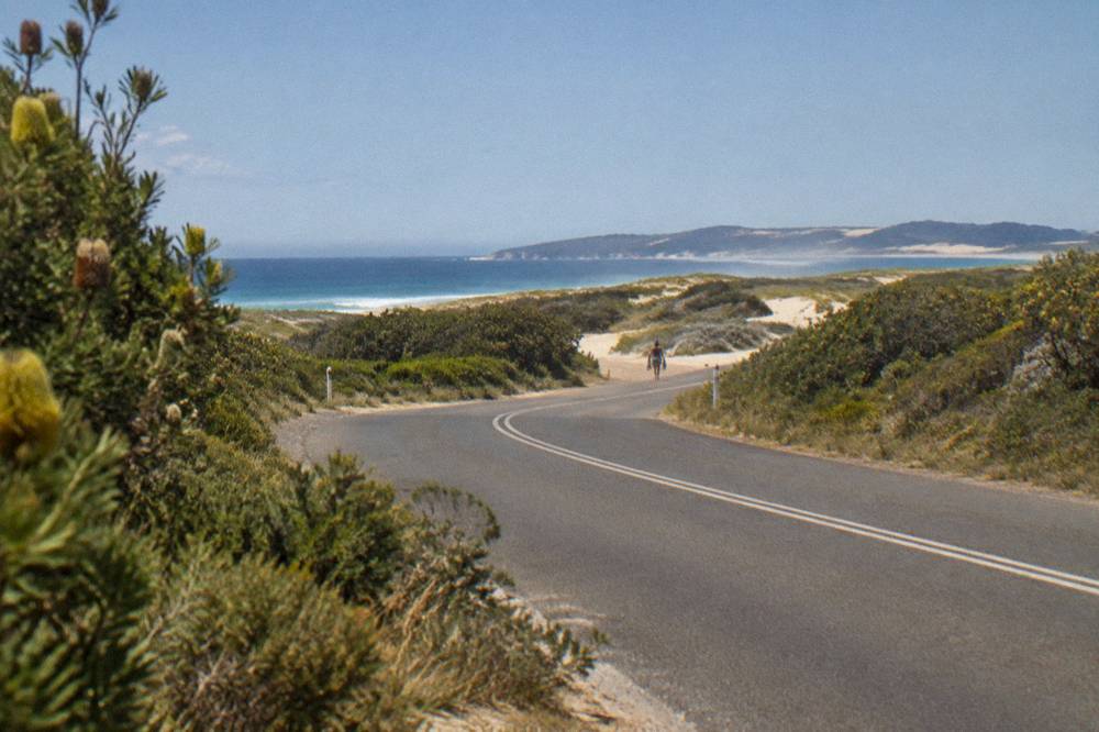 Coastal road curving toward the Port Stephens shoreline with dunes in the distance