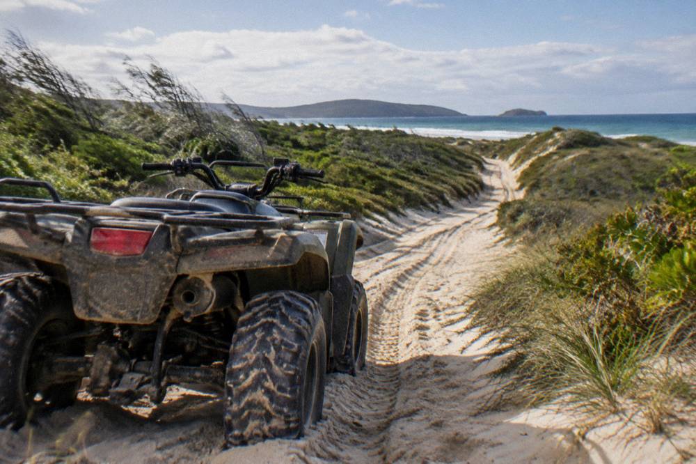 A quad bike parked on a sand track with rolling dune ridges stretching to the horizon