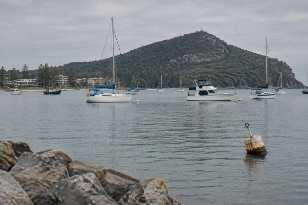 Sheltered bay water at Nelson Bay with boats at anchor and wooded headland beyond