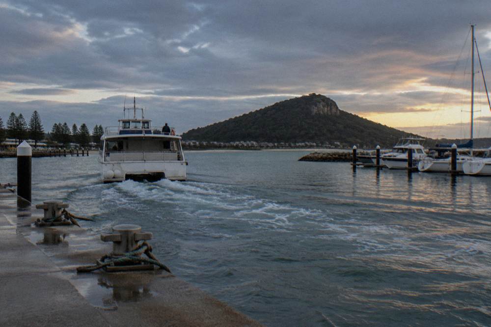 A tour boat leaving Nelson Bay marina across calm sheltered water